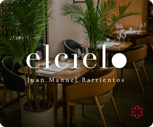 An elegant dining setup at Elcielo by Juan Manuel Barrientos, featuring cozy wooden tables, plush chairs, and lush green plants, with a Michelin star icon prominently displayed.